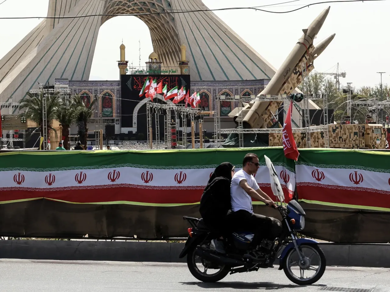 An Iranian couple rides past Iranian-made Zolfaghar missiles displayed at Azadi Square in Tehran on July 24, 2026. Iran's army said on July 24 it carried out drone strikes against several American military facilities and bases in Bahrain and Jordan in retaliation for the latest US attacks against the Islamic republic.