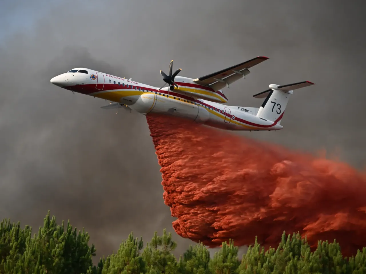 A plane releases fire retardant as it flies over a forest near Blagon, during wildfires in southwestern France, July 29, 2026.