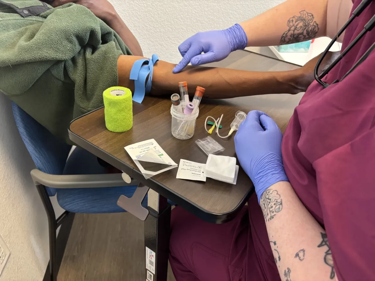 Izzy Kadrmas, a medical assistant at Partnership Health Center's Watershed Clinic in Missoula, Montana, prepares to take Tywon Pugh's blood for testing.