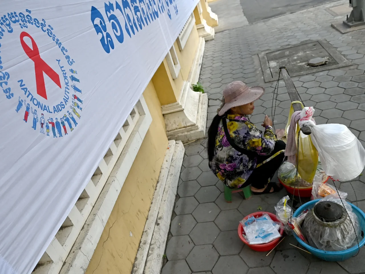 Cambodia is the first country in Asia to meet the U.N. targets for controlling HIV. Above: A vendor in Phnom Penh sits by a banner marking World AIDS Day.