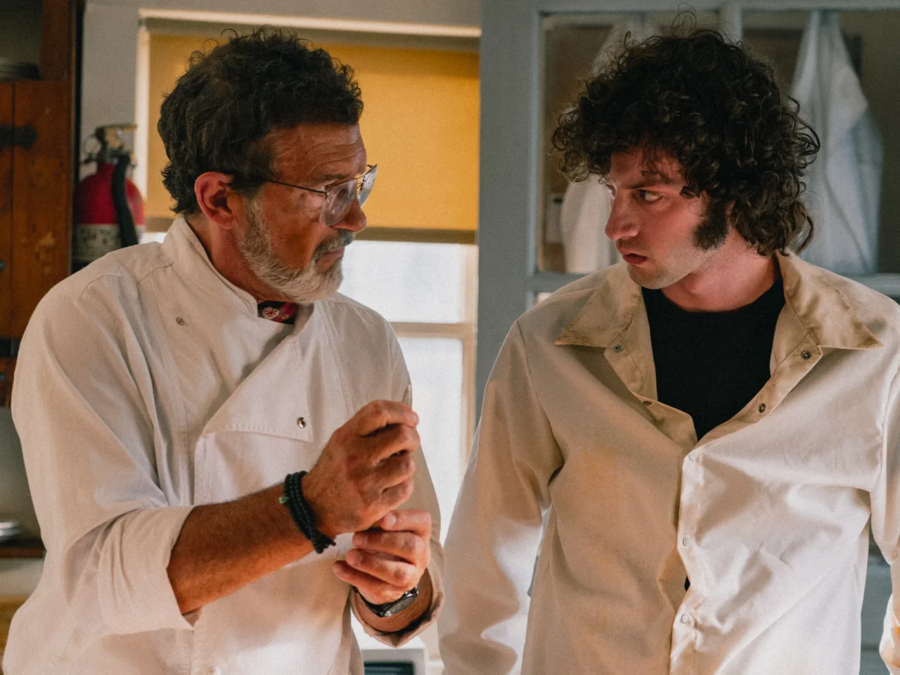 A restaurant's head chef portrayed by Antonio Banderas (left) takes under his wing a 19-year-old Anthony Bourdain, played by Dominic Sessa (right), in Tony.