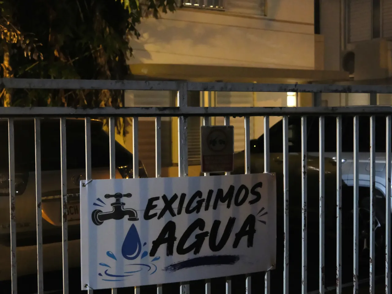 A sign demanding water is affixed to the gates outside the condo building — one building among many across Puerto Rico to which the island's public utility has cut running water.